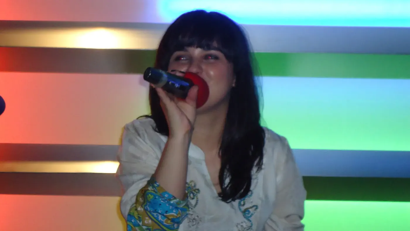 Una clienta cantando con el micrófono entre luces de colores