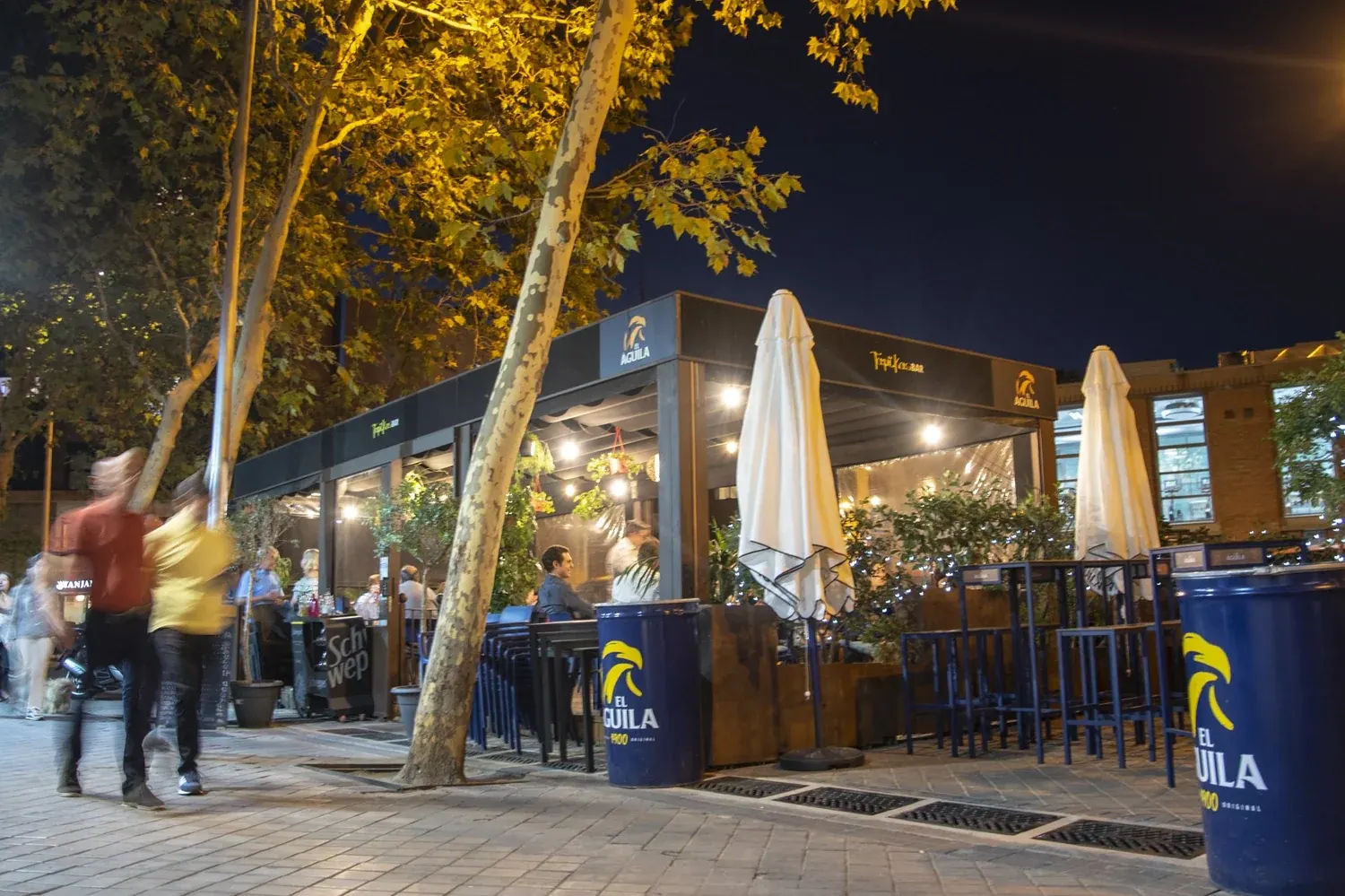 Terraza de Kapikas de noche, con árboles y mesas